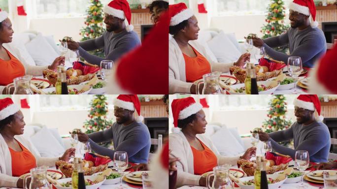 一名戴着圣诞帽的非裔美国男子在向坐在餐桌上的年长女性的杯子里倒饮料