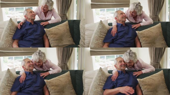 一对老年白种人夫妇在客厅沙发上拥抱微笑的慢镜头