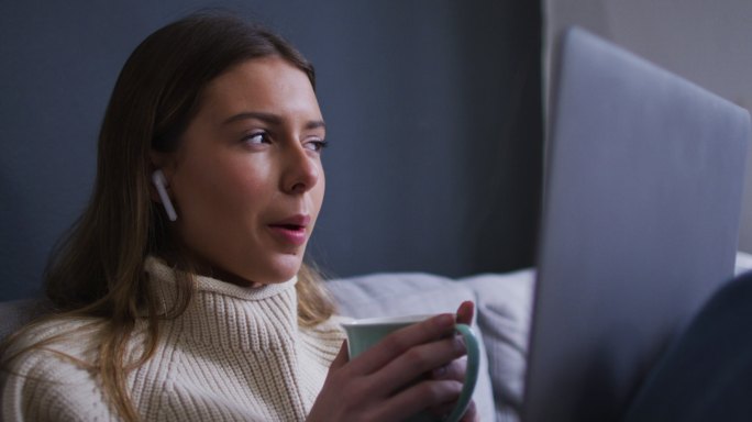 一个女人在家里一边喝咖啡一边用笔记本电脑视频聊天