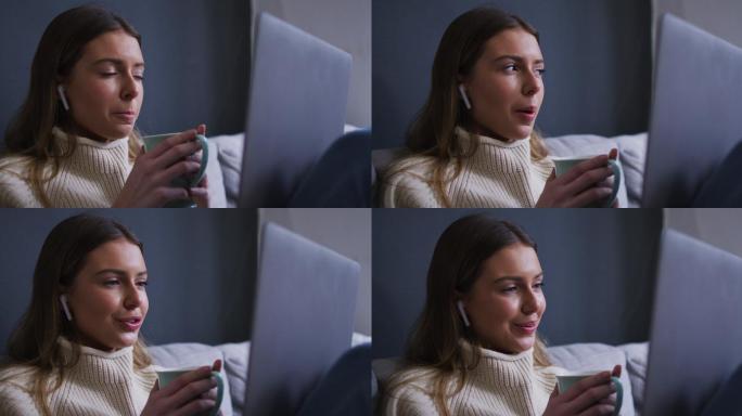一个女人在家里一边喝咖啡一边用笔记本电脑视频聊天
