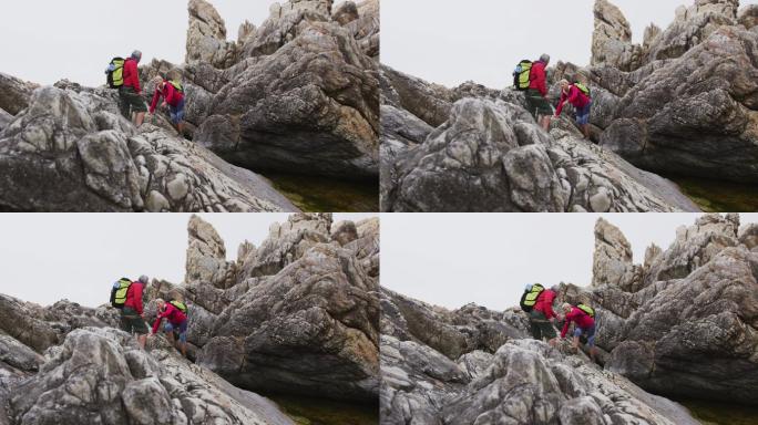 一对背着背包、拄着登山杖的资深徒步夫妇在攀岩时彼此牵着手