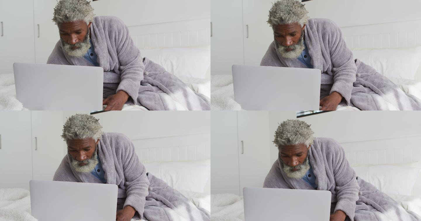 老人在家里的床上使用笔记本电脑