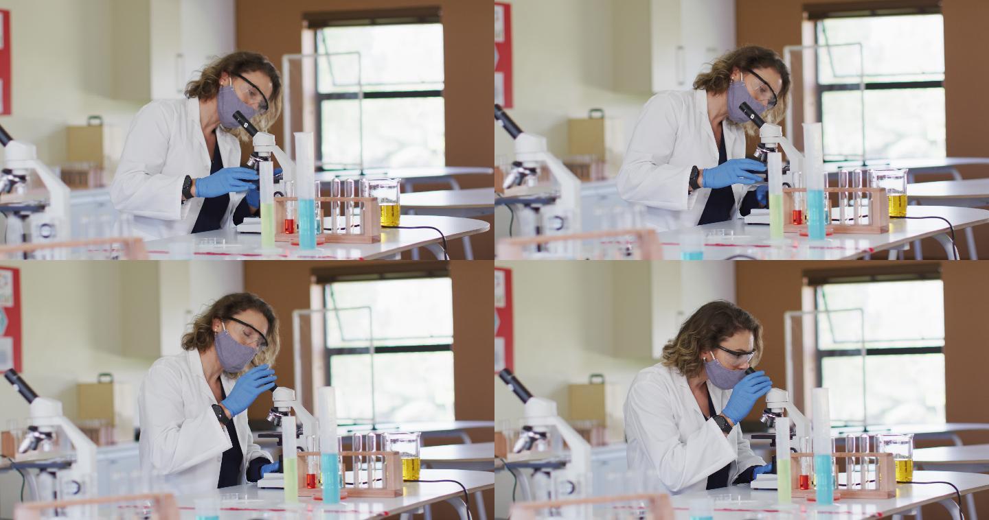 女教师戴口罩在学校实验室使用显微镜