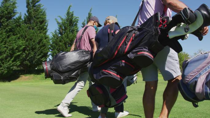 老年人戴着口罩拿着高尔夫球袋在高尔夫球场散步