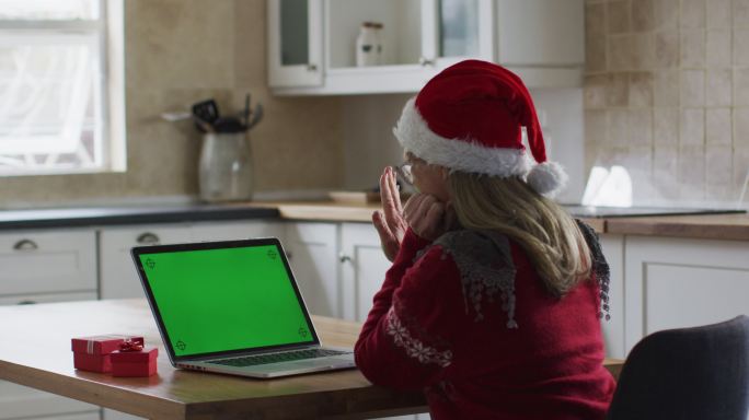 戴着圣诞老人帽的女人正在家里用笔记本电脑视频聊天