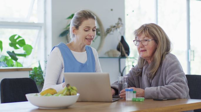 女性健康工作者和资深女性在家里通过笔记本电脑讨论