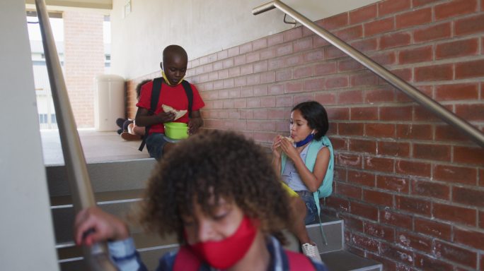 男孩和女孩在学校的楼梯上吃午餐盒饭