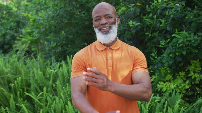 肖像的非洲裔美国高级男子微笑和交叉他的双臂在花园里