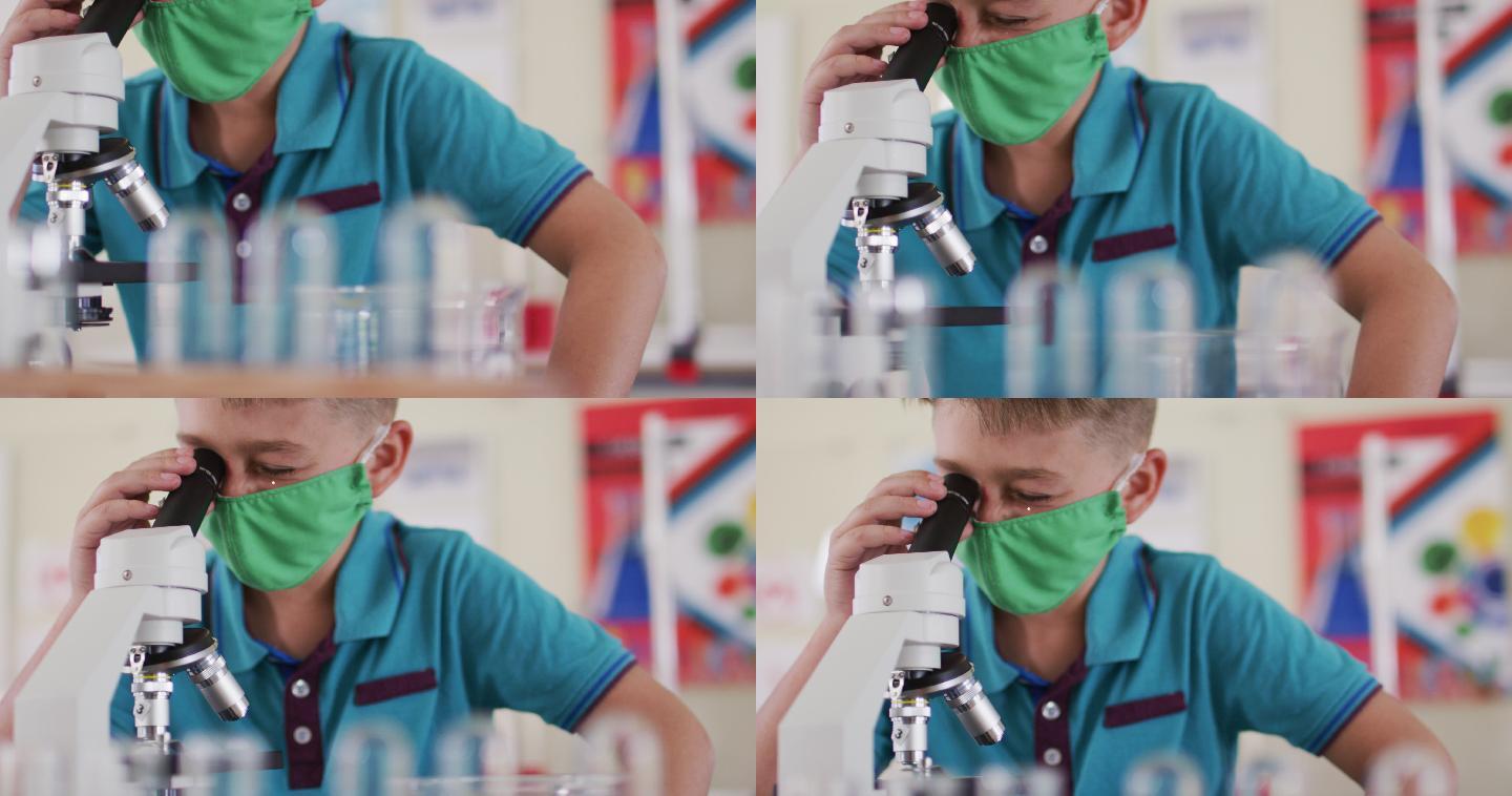 男孩戴着面罩和防护眼镜在实验室里使用显微镜