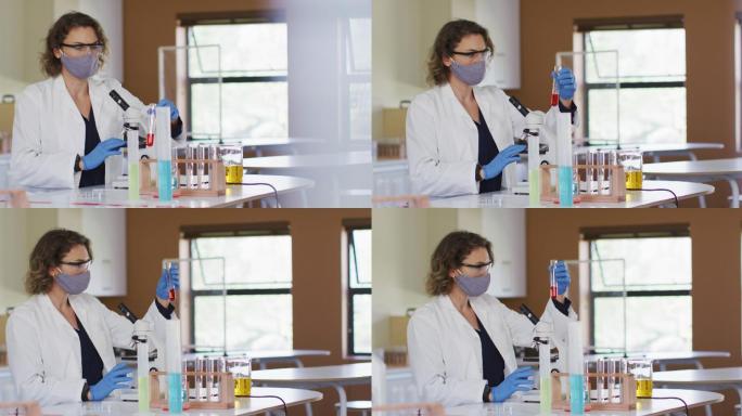 女教师戴着口罩，手持试管在学校的实验室