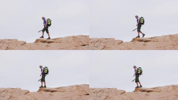 背着背包，拄着拐杖在岩石上行走的资深徒步者