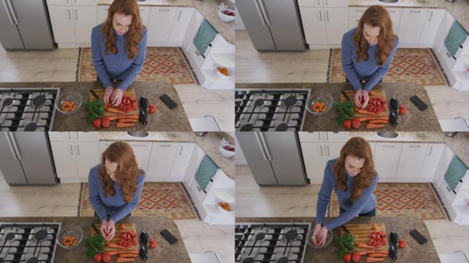 俯视图的女人切蔬菜，并把它放在碗里在厨房