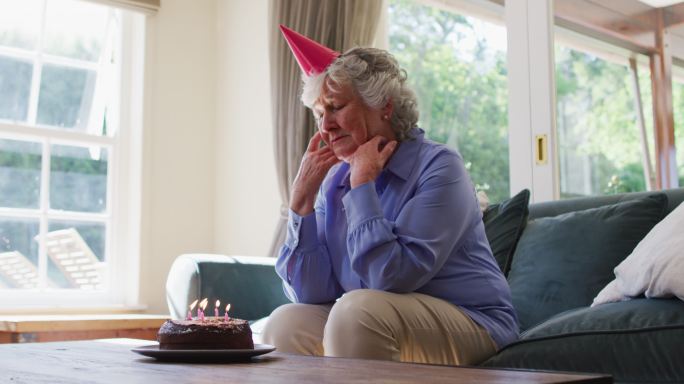 可怜的白人老女人拿着生日蛋糕在家看窗外