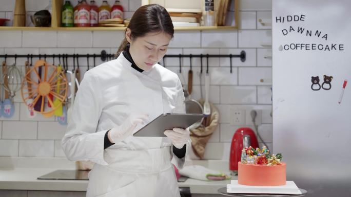 年轻女性烘培师在厨房使用平板电脑