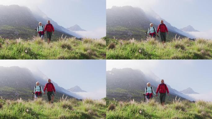 年老的徒步夫妇背着背包和登山杆，在徒步旅行时手牵着手走