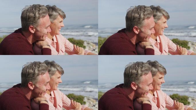 在阳光明媚的日子里，一对白种夫妇坐在海边拥抱，享受自由时光