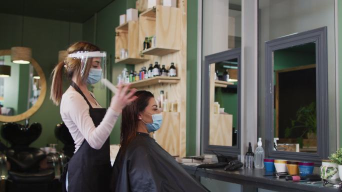 女发型师戴面罩为发廊的女顾客梳头