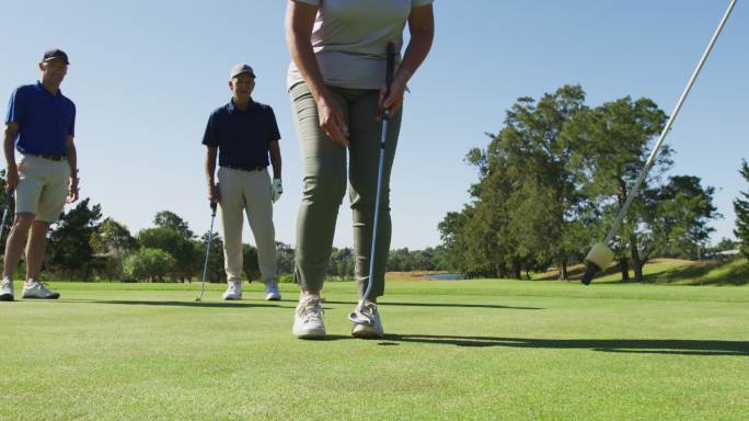 白人高级妇女在一个阳光明媚的日子从高尔夫球场的洞移出高尔夫球