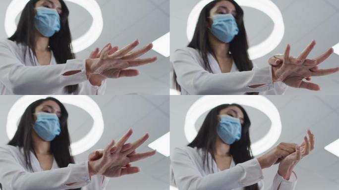 一名妇女戴着口罩在办公室给双手消毒