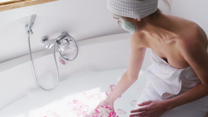 一个女人敷着面膜，在浴缸里撒玫瑰花瓣