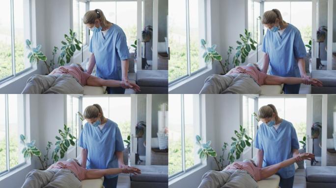 女性卫生工作者在家中伸展老年妇女的手臂