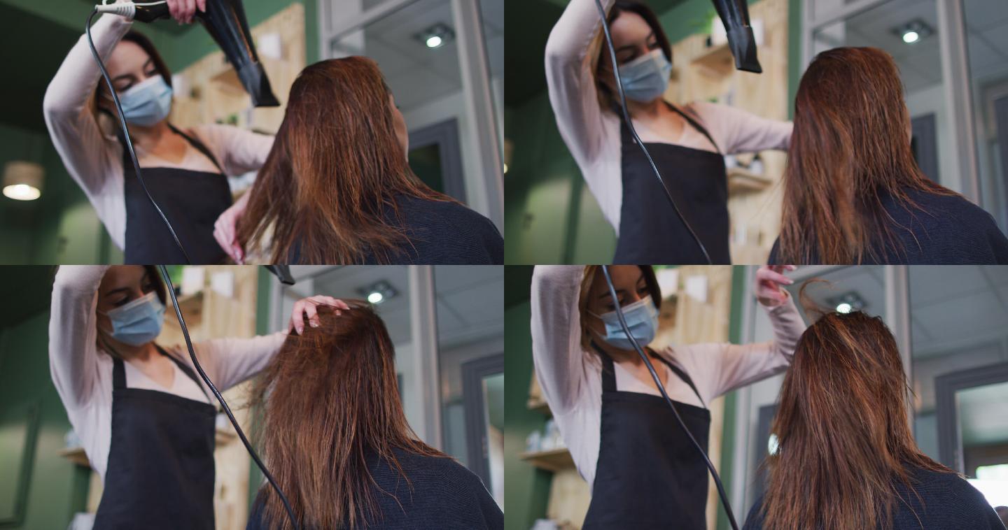 女发型师戴着面罩在发廊为女顾客吹干头发