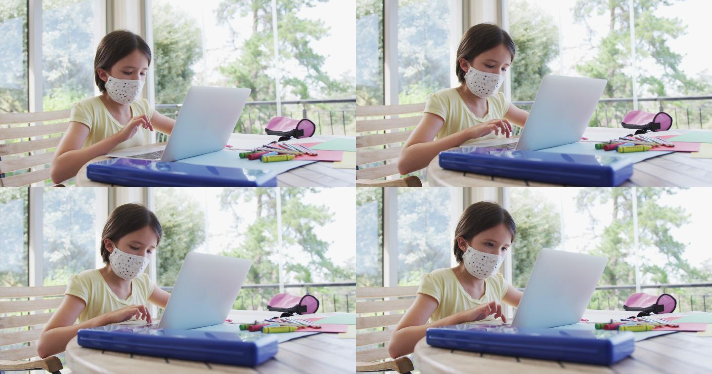 女孩戴着口罩在家里用笔记本电脑