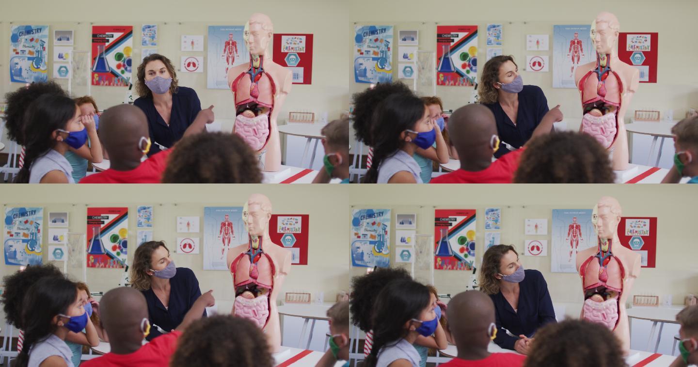 女老师戴着口罩用人体解剖模型给学生上课