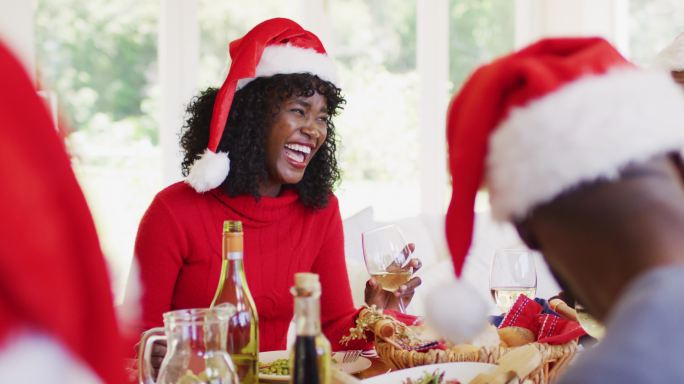 非裔美国老人和戴着圣诞帽的年轻女子坐在迪宁上谈笑风生