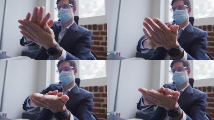 一名男子戴着口罩在办公室给双手消毒