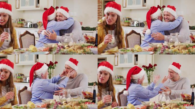 白种老妇人在圣诞老人的帽子拥抱她的儿子，而坐在餐桌上享受午餐