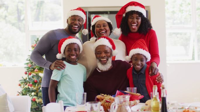 非裔美国家庭戴着圣诞帽在家一起微笑的肖像