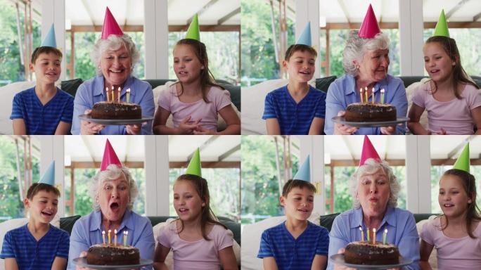 白种老妇人在派对帽子吹蜡烛在生日蛋糕，而她的孙子坐在