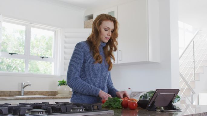 在厨房里用平板电脑切水果的女人