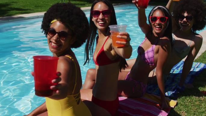 一组不同的女孩的画像，拿着饮料，而坐在游泳池