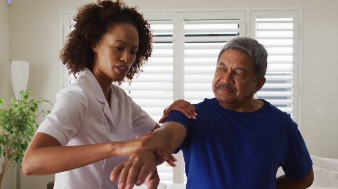 混血女理疗师帮助年长男子伸展手臂