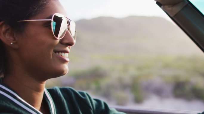 一位非洲裔美国妇女开着敞篷车在乡间小路上行驶