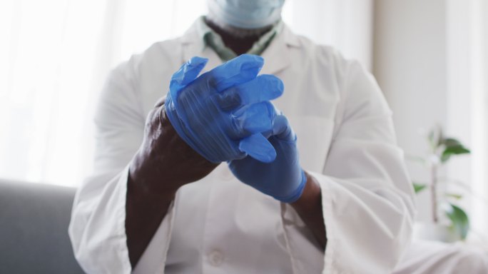 中部男性非裔美国医生戴着外科手套在家