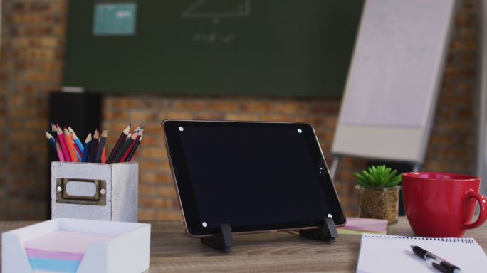 在学校教室的桌子上的数字平板电脑和其他学习用品的视图