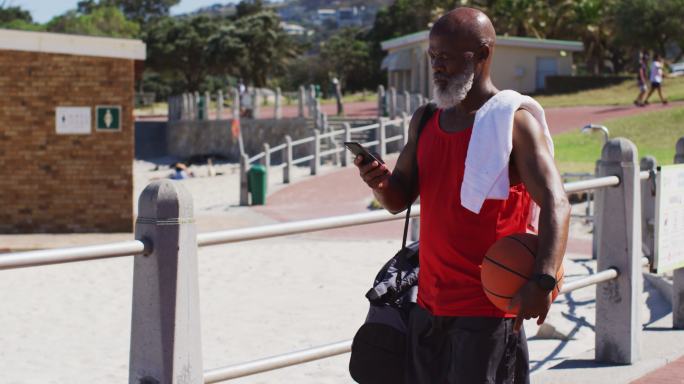 高级非洲裔美国人一边打篮球一边用智能手机聊天