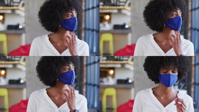 一位戴着面罩的非裔美国妇女坐在咖啡馆看窗户