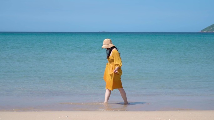 夏天的海南万宁，一个黄裙子美女在海边散步