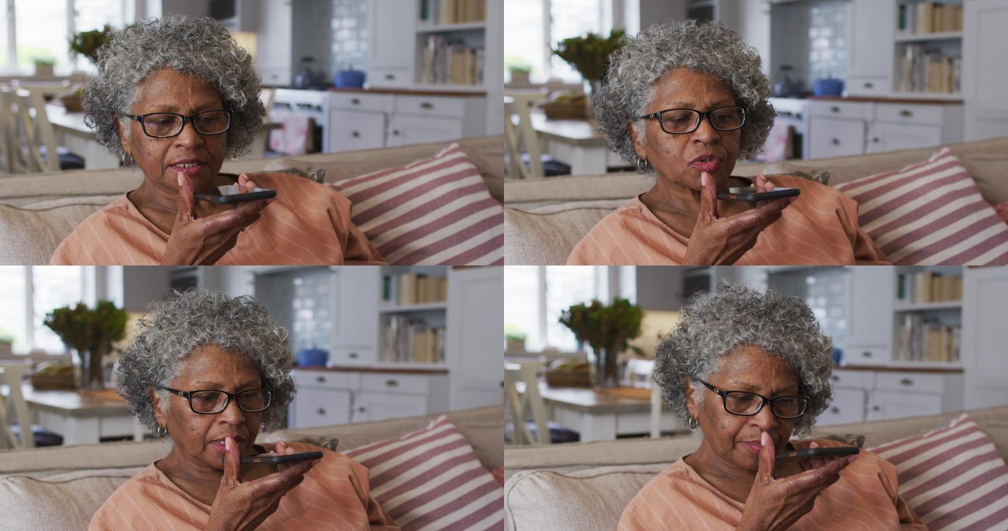 一位非裔美国资深女性坐在家里的沙发上用智能手机聊天