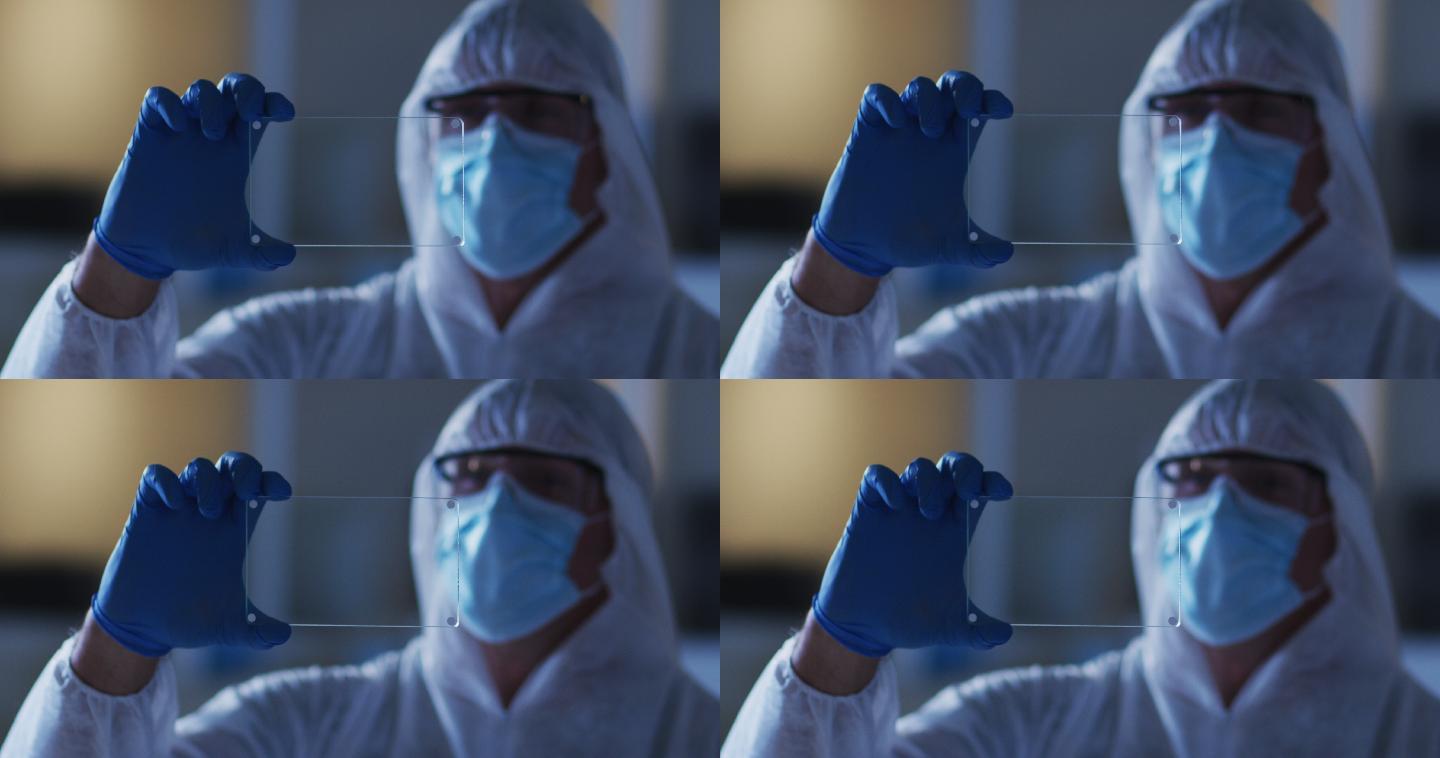 白种男性医务工作者，穿着防护服，戴着手套，在实验室使用手持接口