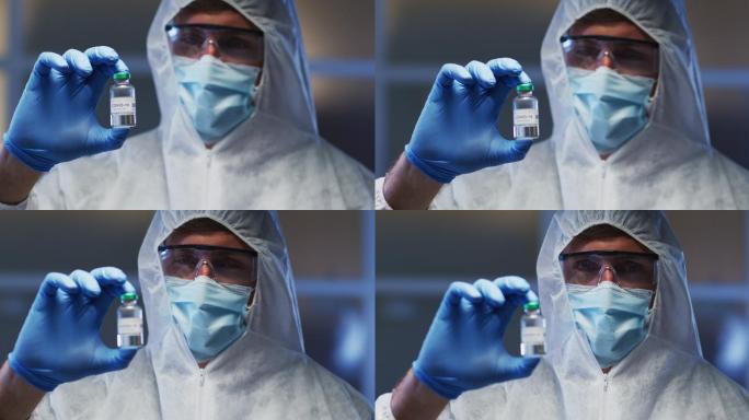 白人男性医务工作者，穿着防护服，戴着口罩和手套，手里拿着疫苗小瓶