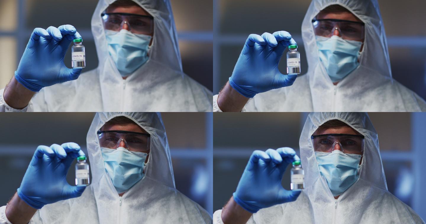 白人男性医务工作者，穿着防护服，戴着口罩和手套，手里拿着疫苗小瓶