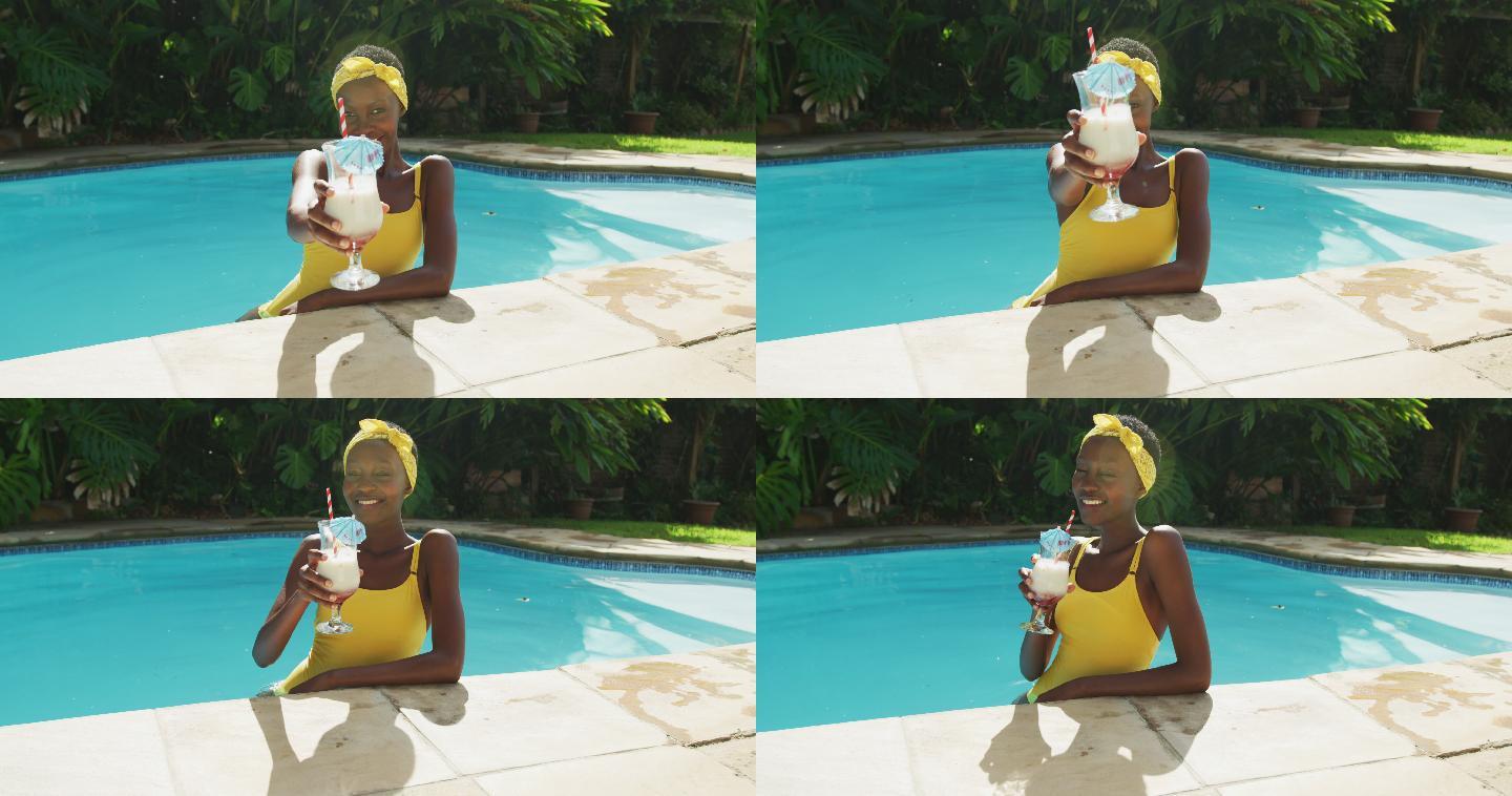 一个快乐的非洲裔美国妇女站在游泳池用她的饮料敬酒的肖像