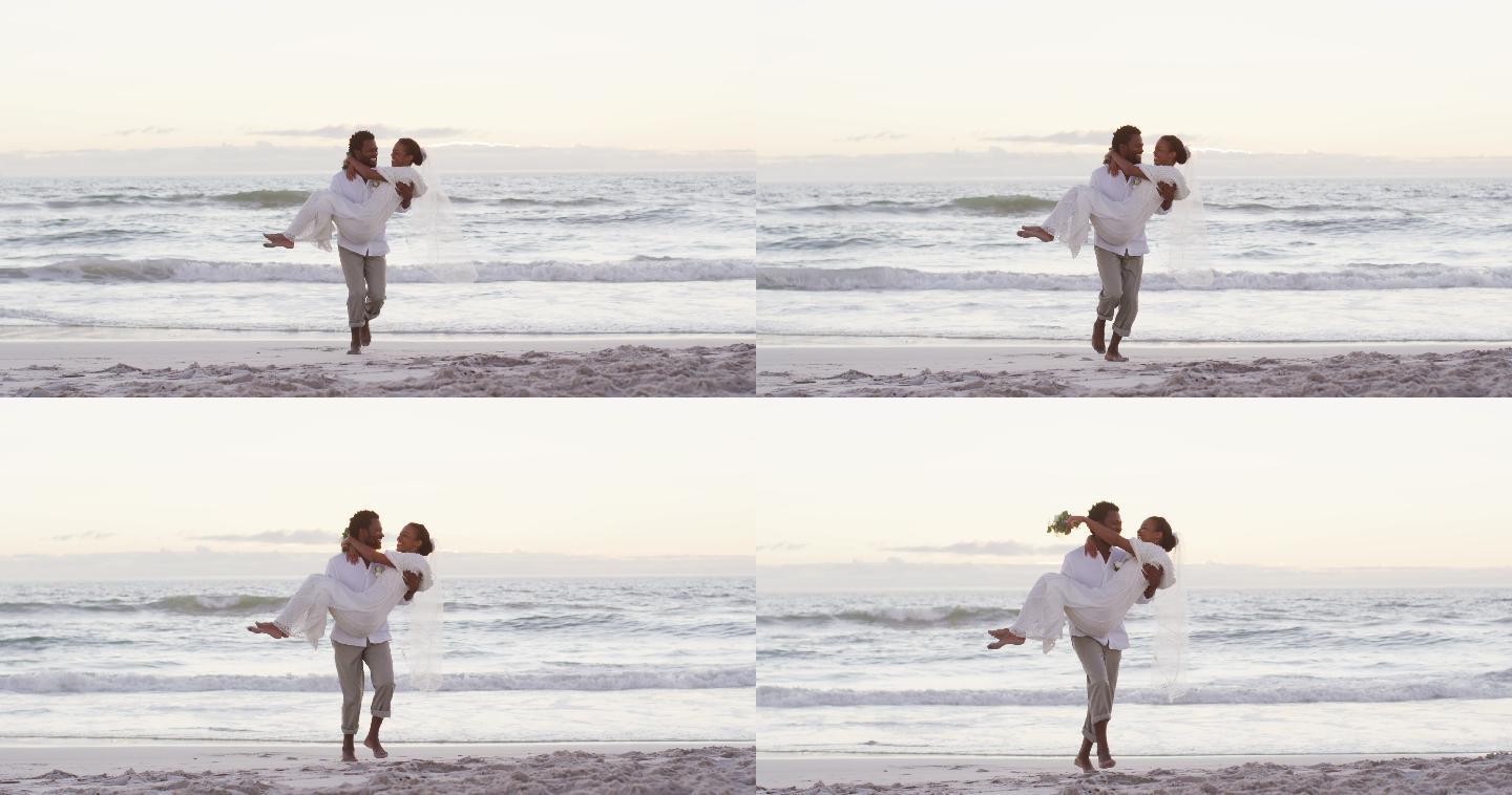 非裔美国情侣在结婚，男人抱着女人在日落的海滩上