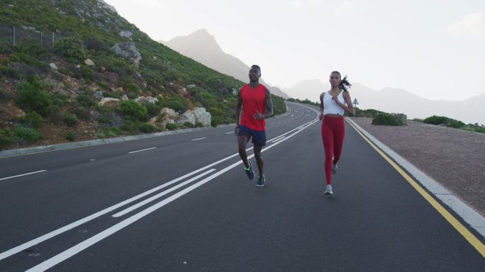 不同的健康夫妇锻炼跑步在一个乡村道路附近的山