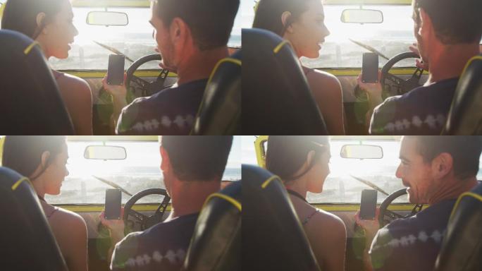 幸福的白人夫妇坐在沙滩车在海边使用智能手机